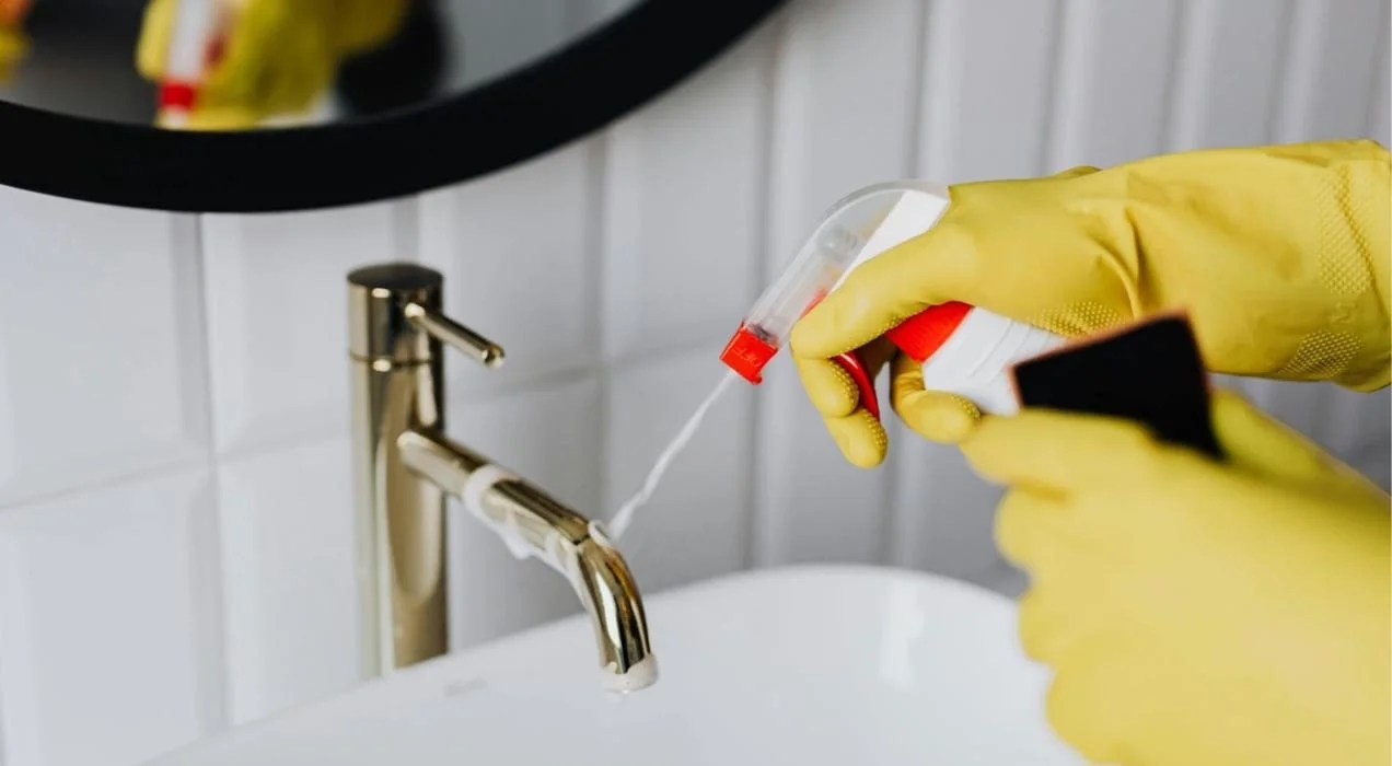 someone cleaning a sink with gloves