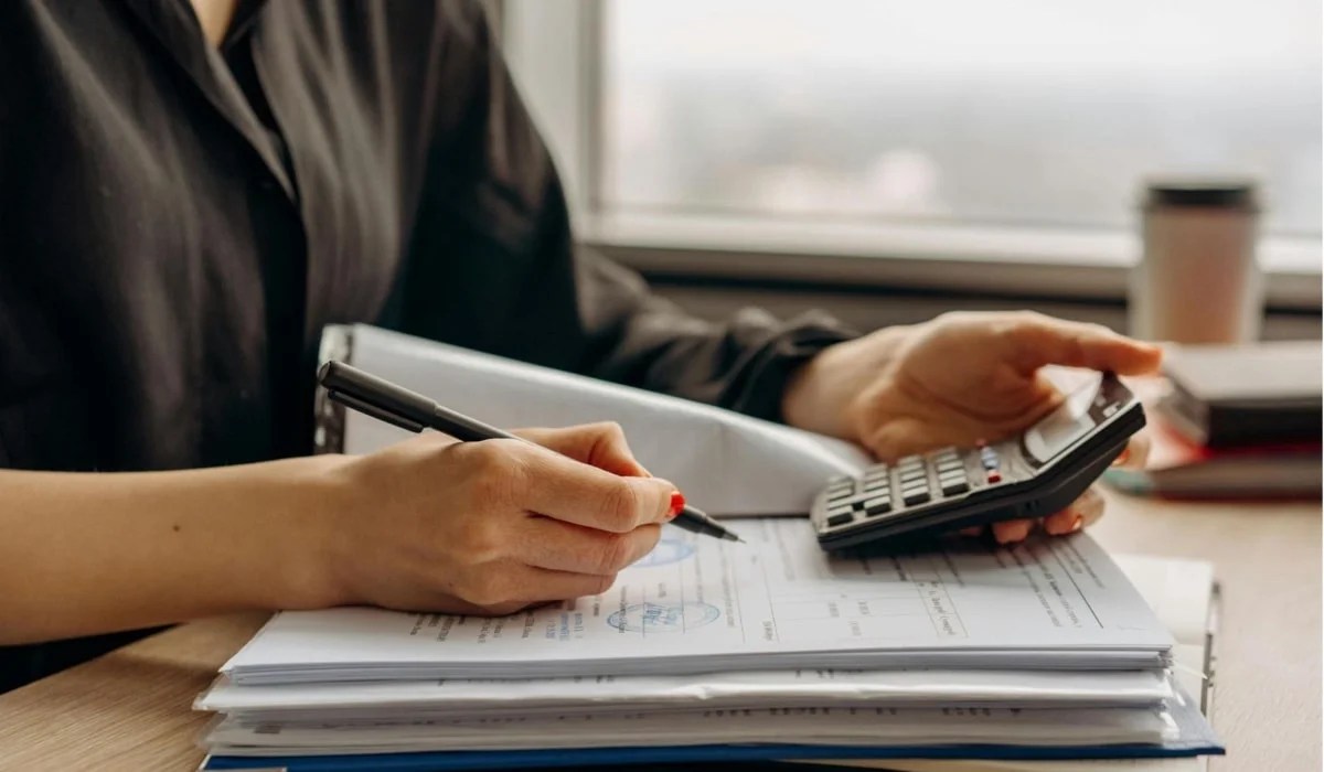 woman using a calculator and filling out forms