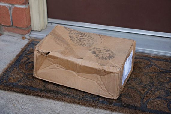 Image of a footprint on a smashed delivery box on a doorstep 